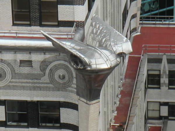 A metallic eagle head juts from the Chrysler Building’s corner, showcasing detailed Art Deco features and geometric patterns.