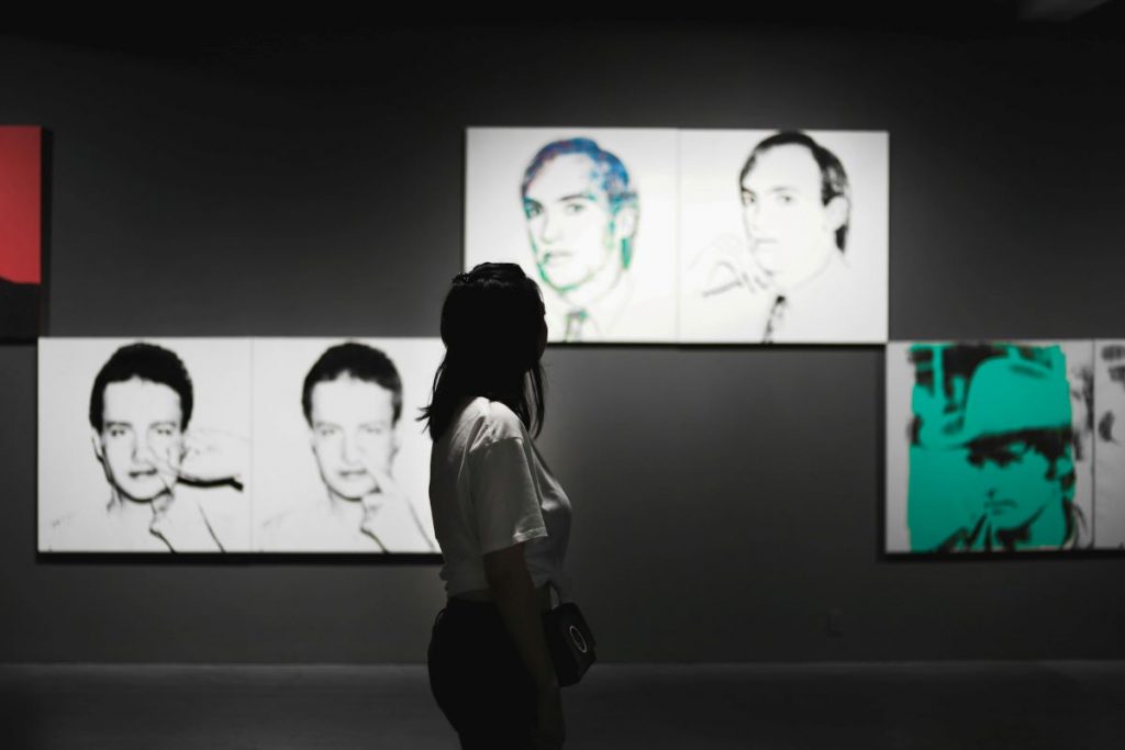 woman looking at Andy Warhol artworks at the Modern Art Museum in NYC