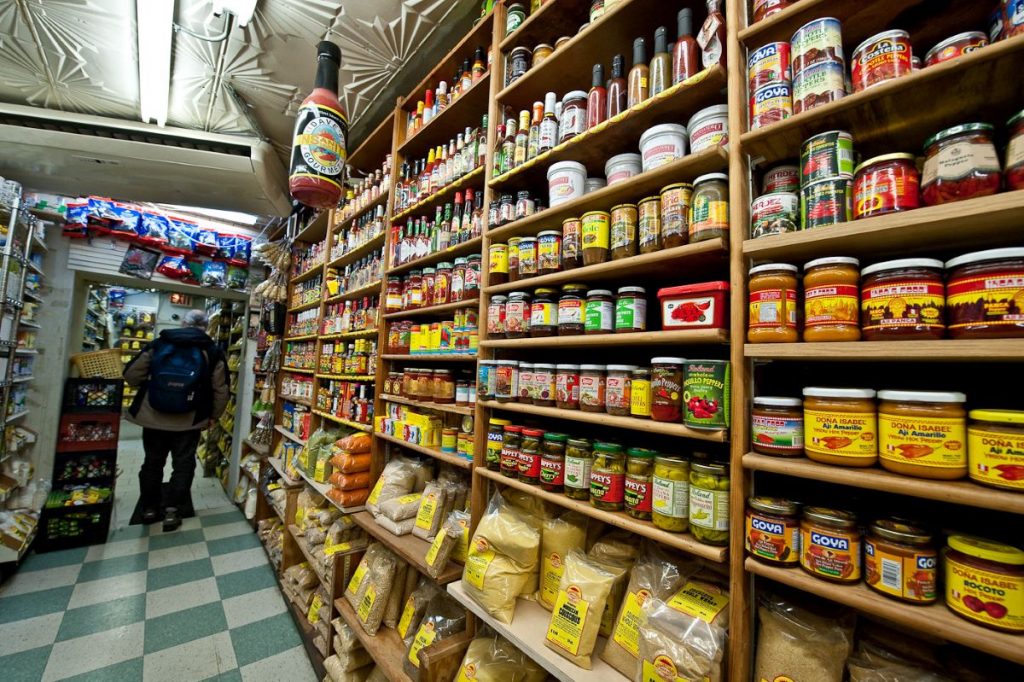 A man walking down the aisle of Kalustyan market in NYC.