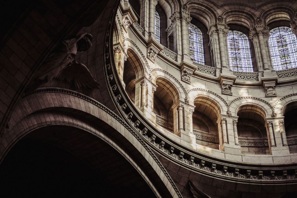 A close-up inside view of the Basilica of the Sacred Heart of Paris, focusing on its intricate walls, arches, and windows