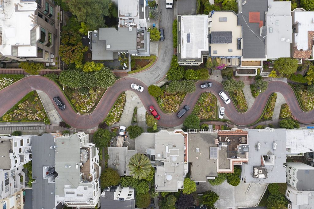 Lombard STreet, one of the unique things to do in San francisco. An aerial photo of this famous streets, , with a number of cars driving round the hairpin bends, and the gardens and roofs of the houses of local reidents. 