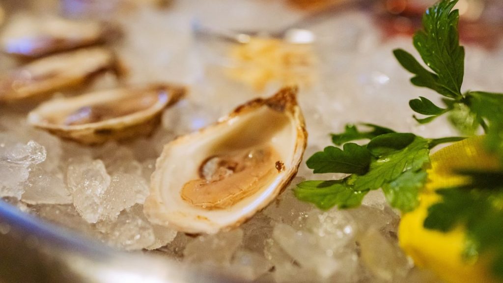 Oysters on ice, with a garnish and lemon wedge on the side, one of the more traditional ways to be served them in oyster bars in London