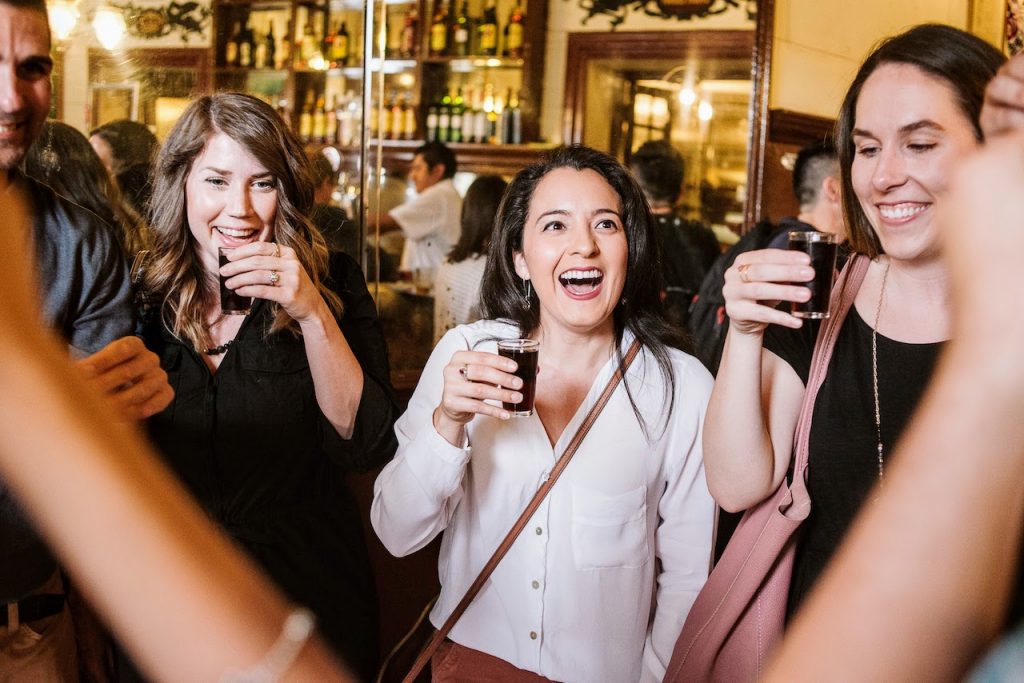 Group of friends sipping small glasses of Spanish vermouth inside of a 100-year-old Madrid neighborhood bar