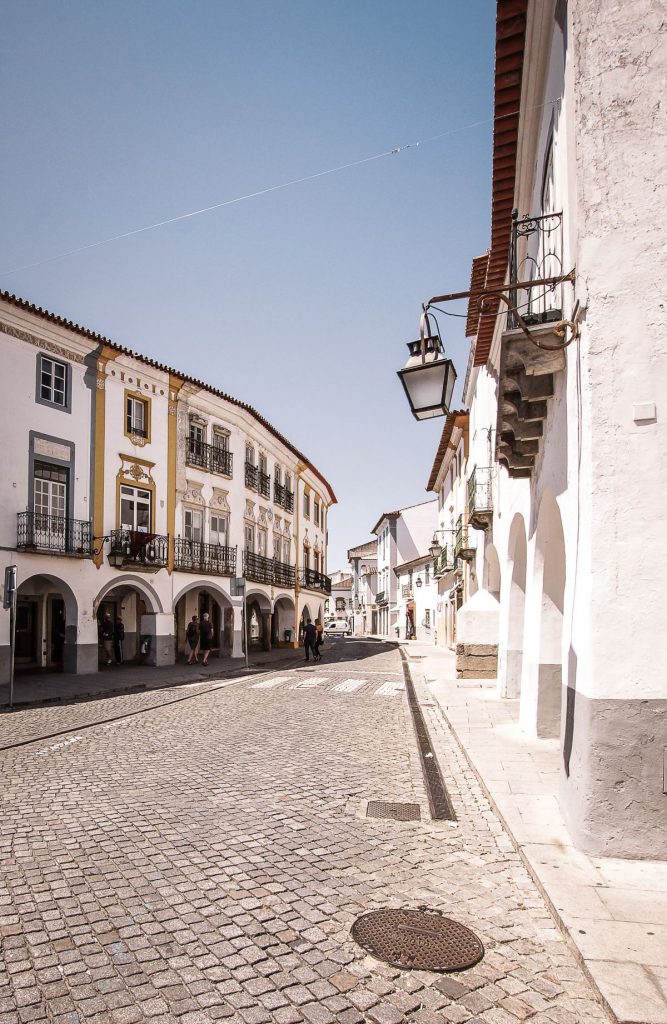 A cobbled street with white buildings, in a town with many things to do, in Evora, Portugal