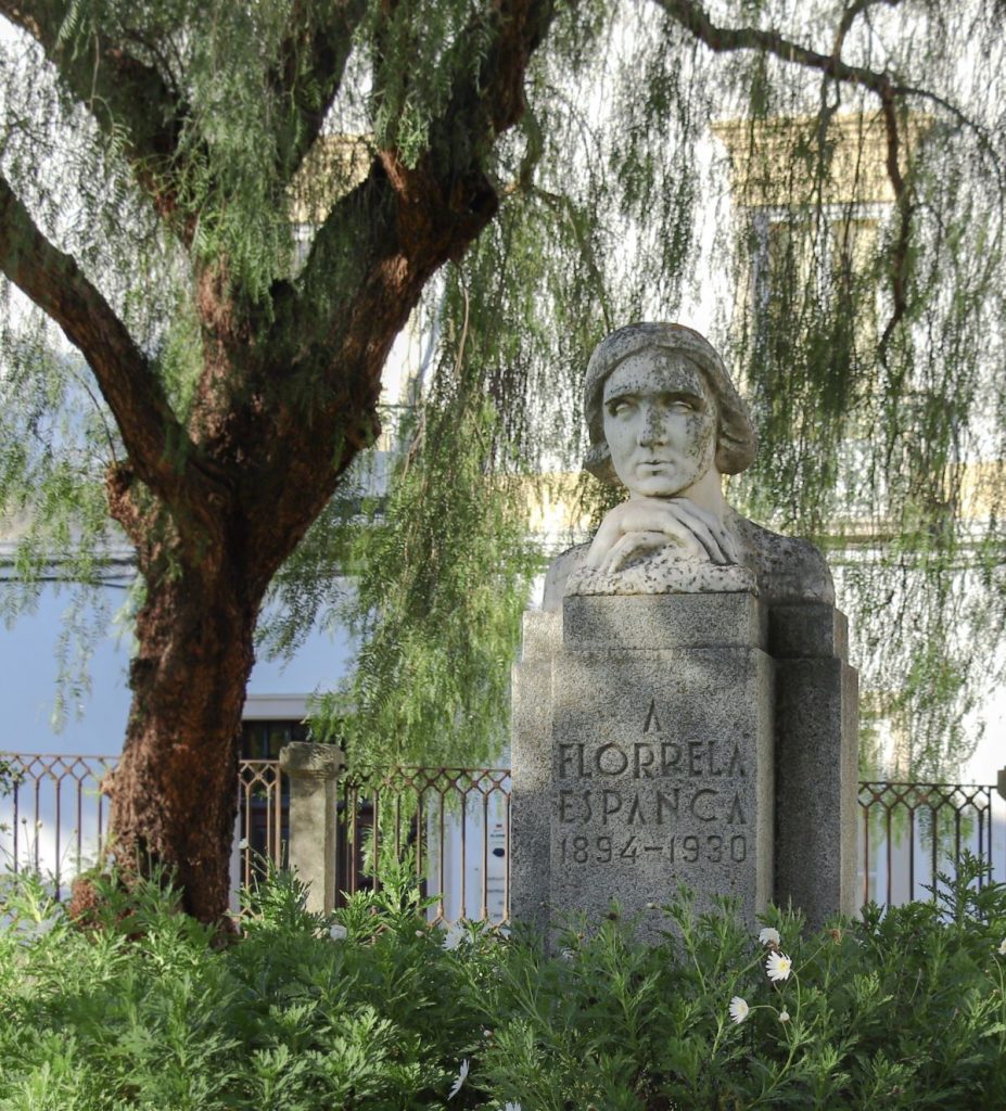 A stone bust of poet Florbela Espanca sits atop a pedestal in the public gadren, one of the more relaxing things to do in Évora, Portugal