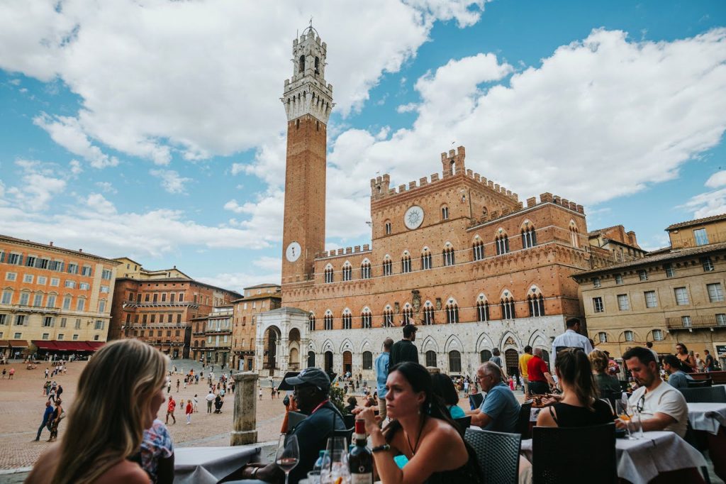People enjoying the views of Torre del Mangia in Siena while on a day trip from Florence.