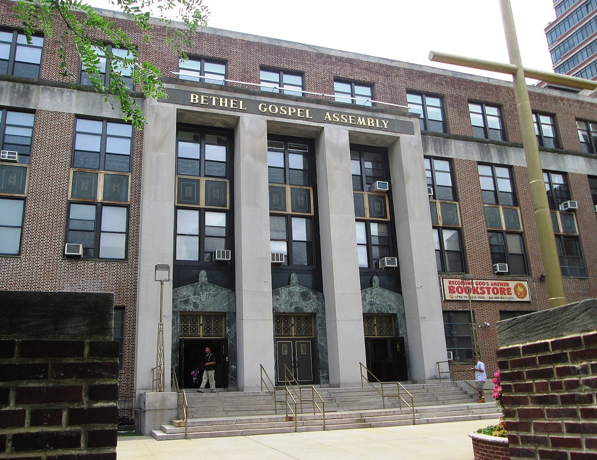 an imposing building with 4 large columns topped with a mantle saying Bethel Gospel Assembly, With larger cross outside