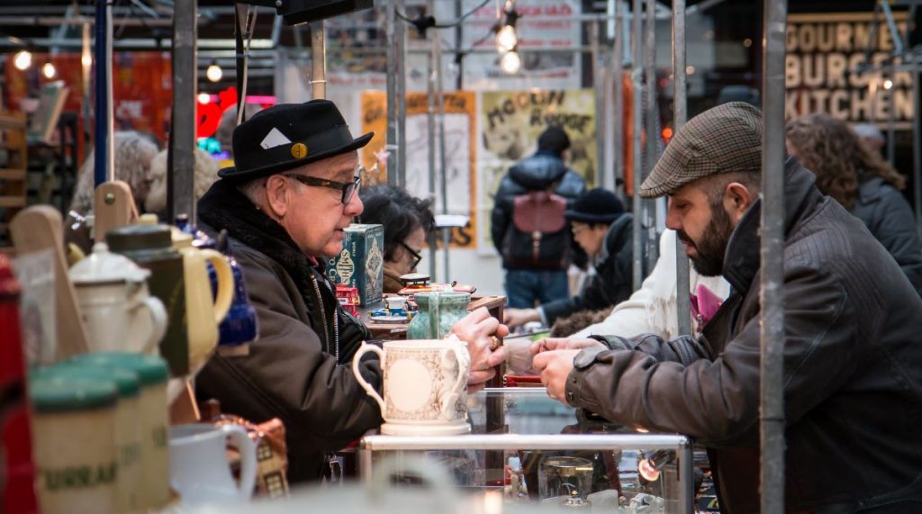 Two people bartering at antiques markets in London.