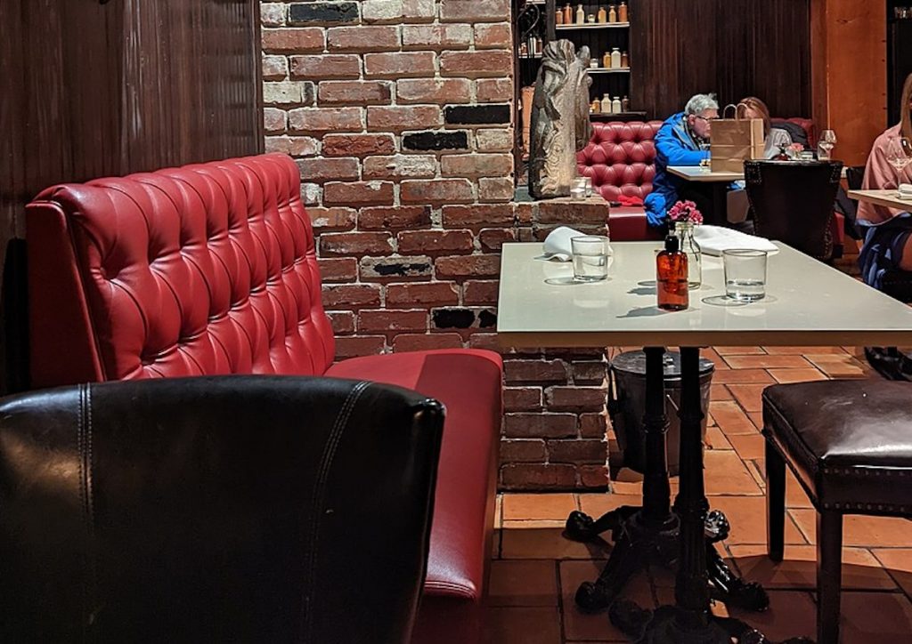 Red booth bench chair and open brick walls inside DC´´s oldest continually operating restaurant- Iron Gate, one of the top historic restaurants in DC
