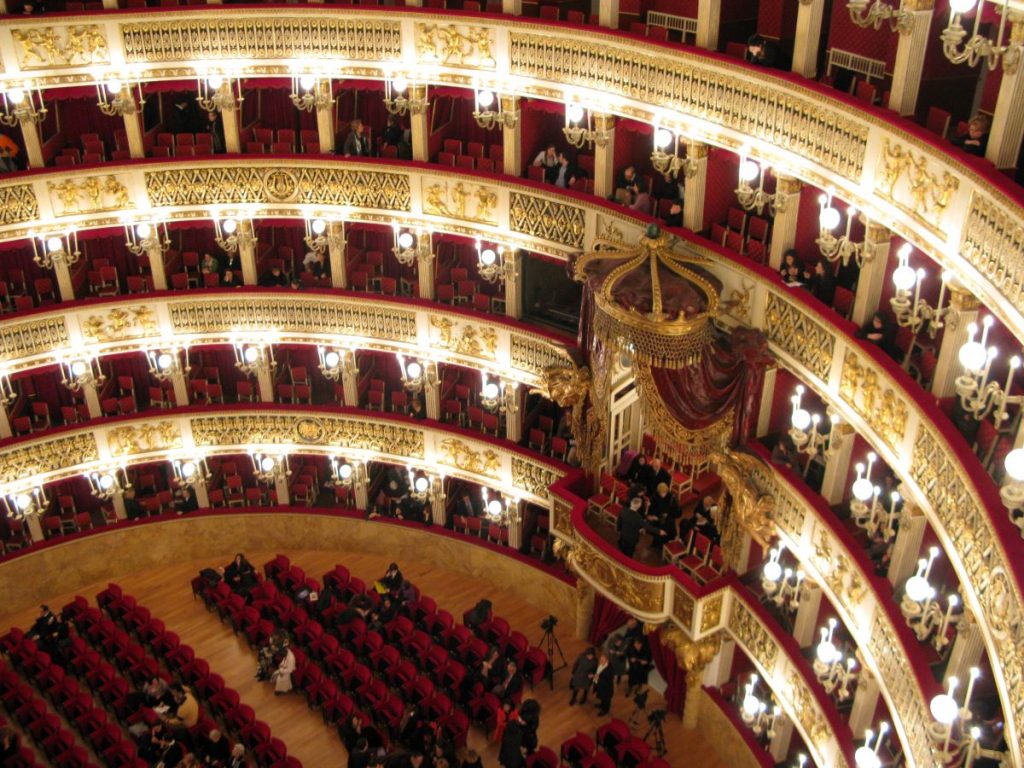 the ornate tiers of seats and balconies in red, cream and gold. and a royal box, in the auditorium of the Teatro di San Carlo, in Naples Italy. It is known for being the oldest opera theater in the world