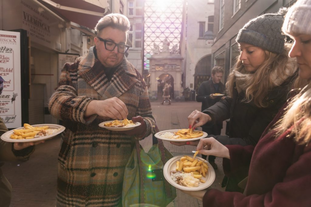 Travelers try typical street food on a food tour in Amsterdam.