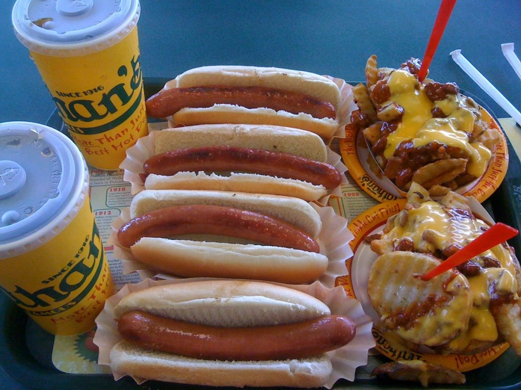 Four hot dogs in buns, cheesy crinkle-cut fries, and two fountain drinks from Nathan’s Famous at Coney Island, which is on the Brooklyn Food tour recommendations 