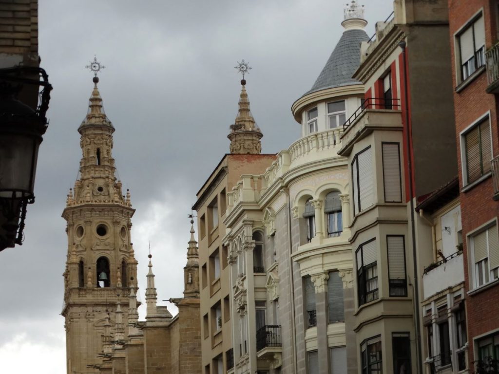 Ornate historical buildings and church towers with stone and brick facades line a street in the picturesque town of Logrono, which is a short day trip from San Sebastian.