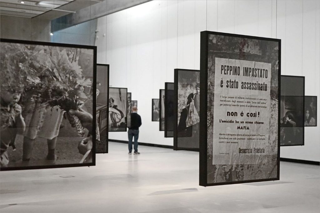 A photography installation that hands from the ceiling and at the end a man can be seen enjoying the artwork.