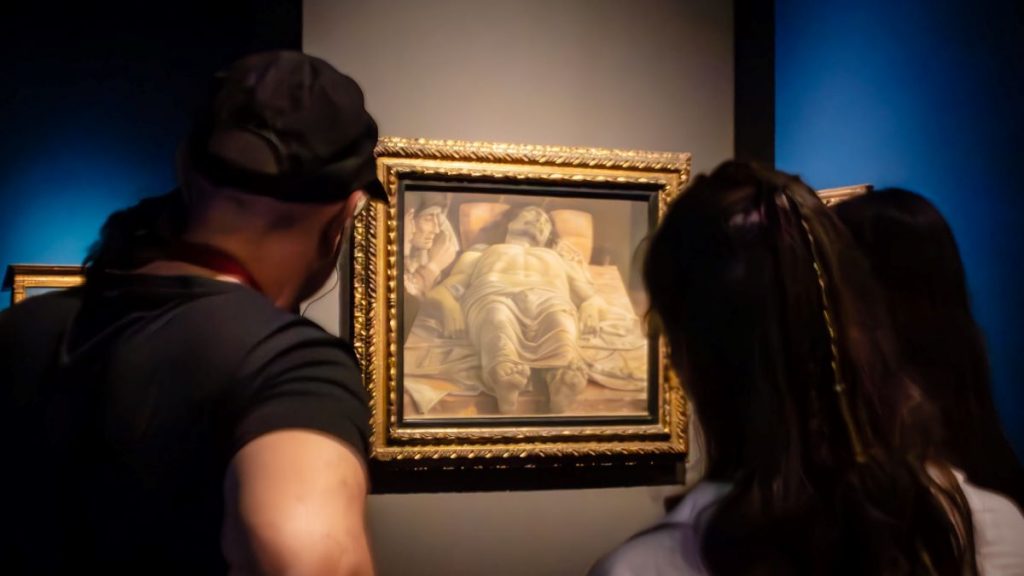 A group of people admiring artwork by Mantegna.