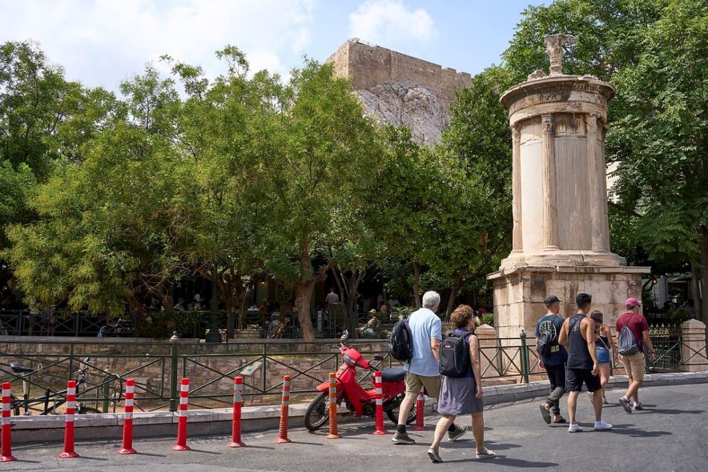 A group of people walking past the Lysicrates monument.