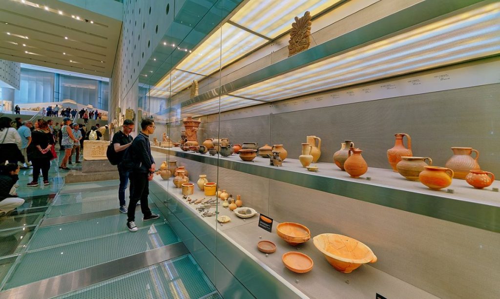 People looking at pottery from the Acropolis at the Acropolis Museum.
