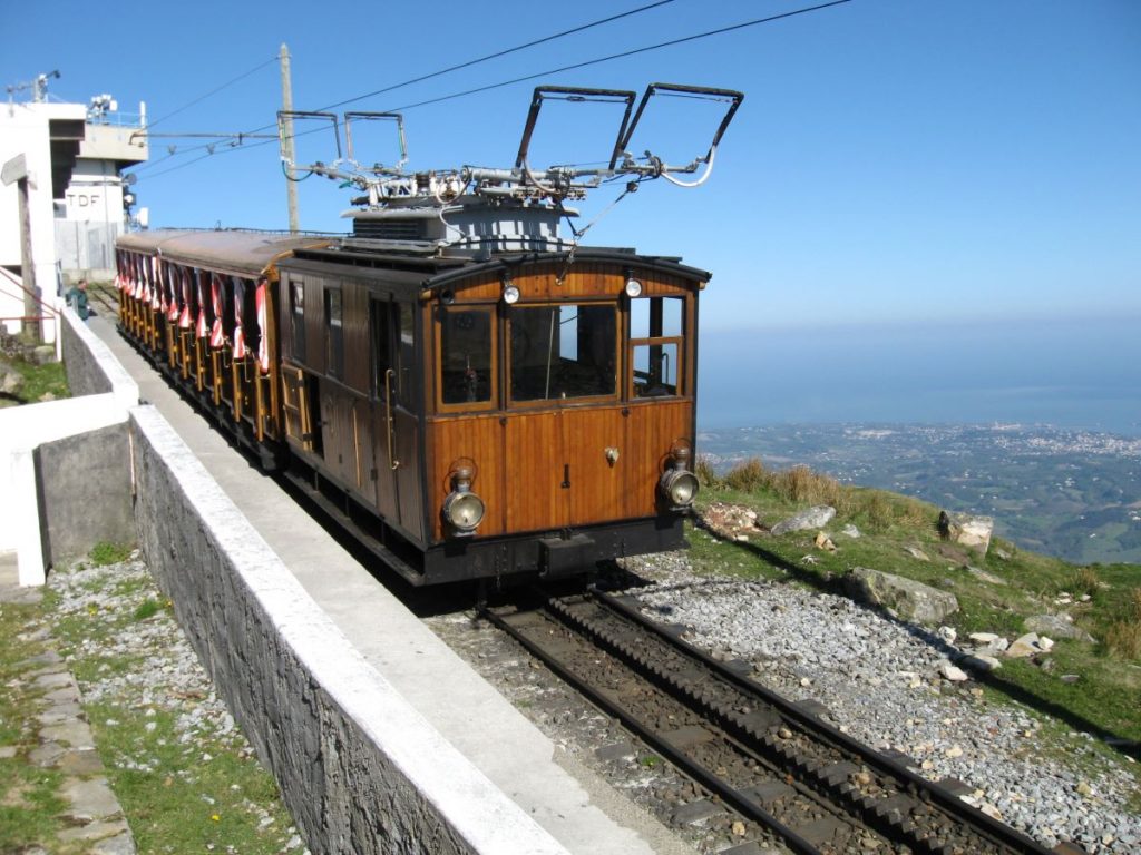 Wooden train on tracks of a mountain route in the French Basque Country with a view of the distant ocean in the background