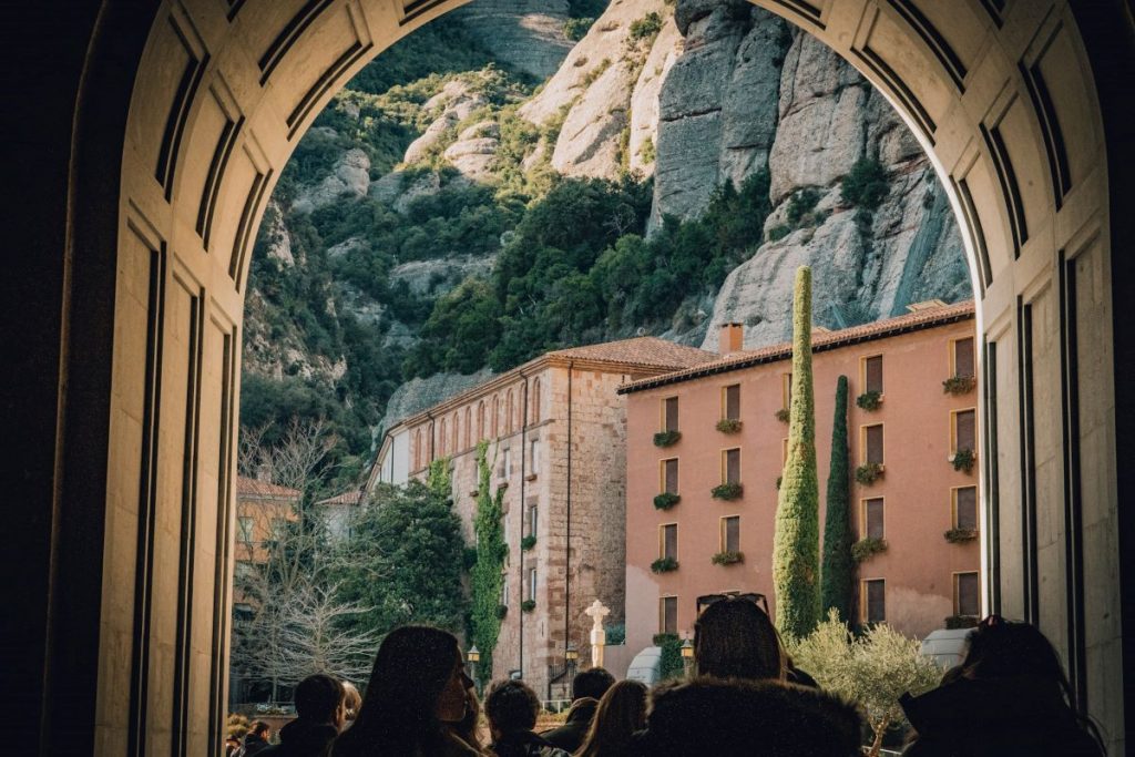 People walking to Montserrat under an archway.