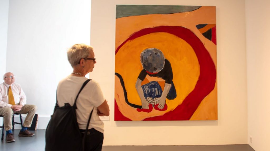 A woman looking at an art piece made by Sean Scully.