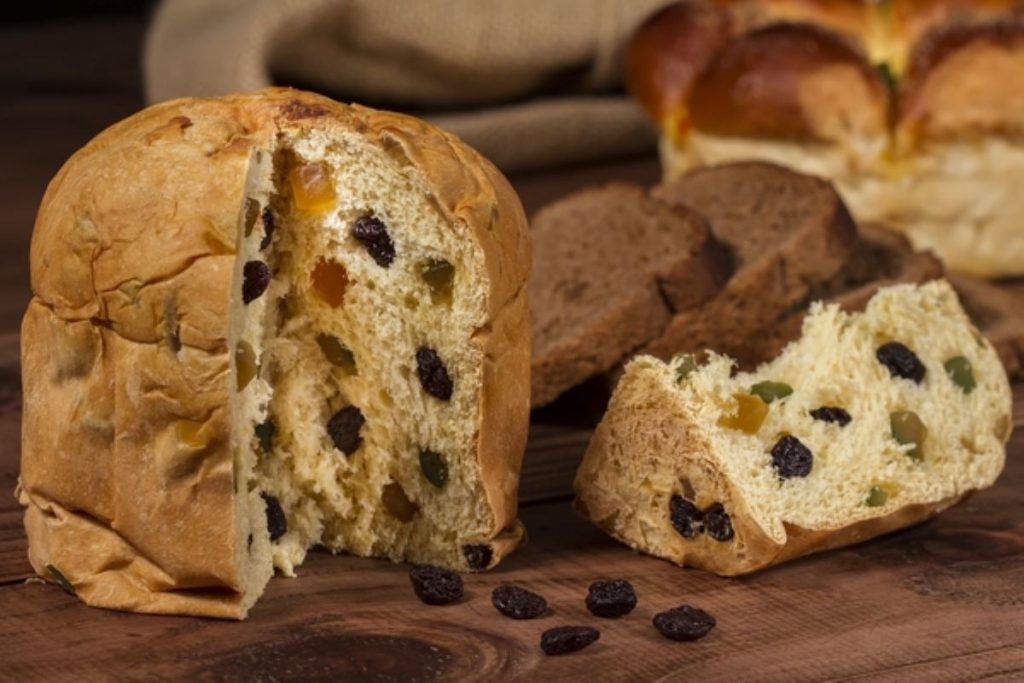 a small panettone, with a portion cut out to show the mixed fruit inside.