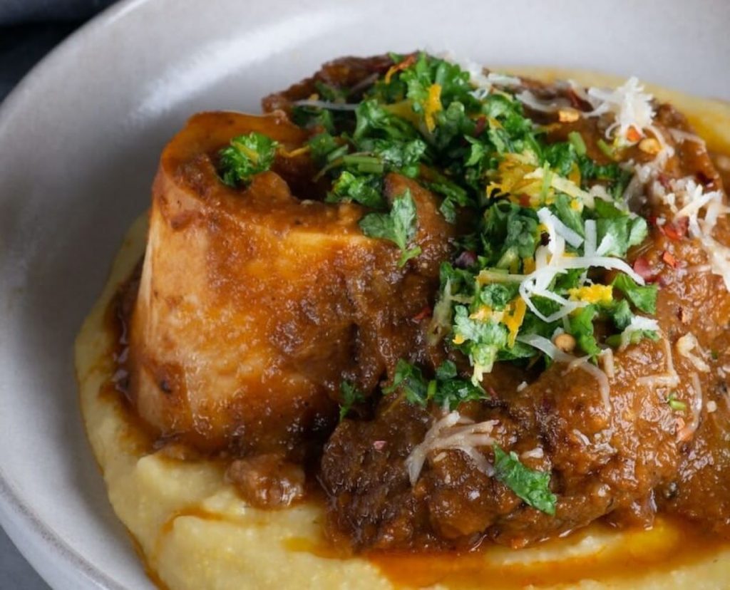 A plate of polenta topped with stewed meat.