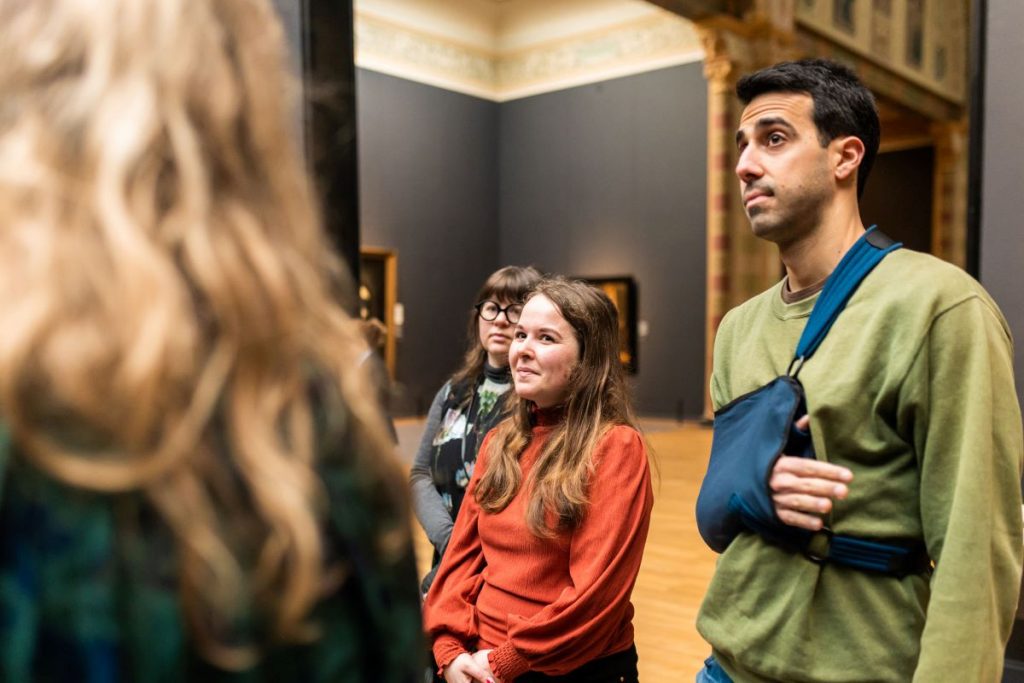 A group of people looking at a few famous paintings.