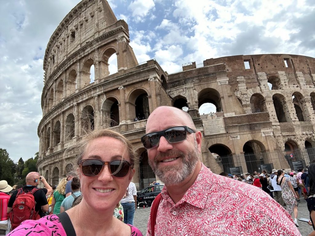 Amy H. and her husband in front of the Colosseum in Rome, exploring Europe with Walks Tours.