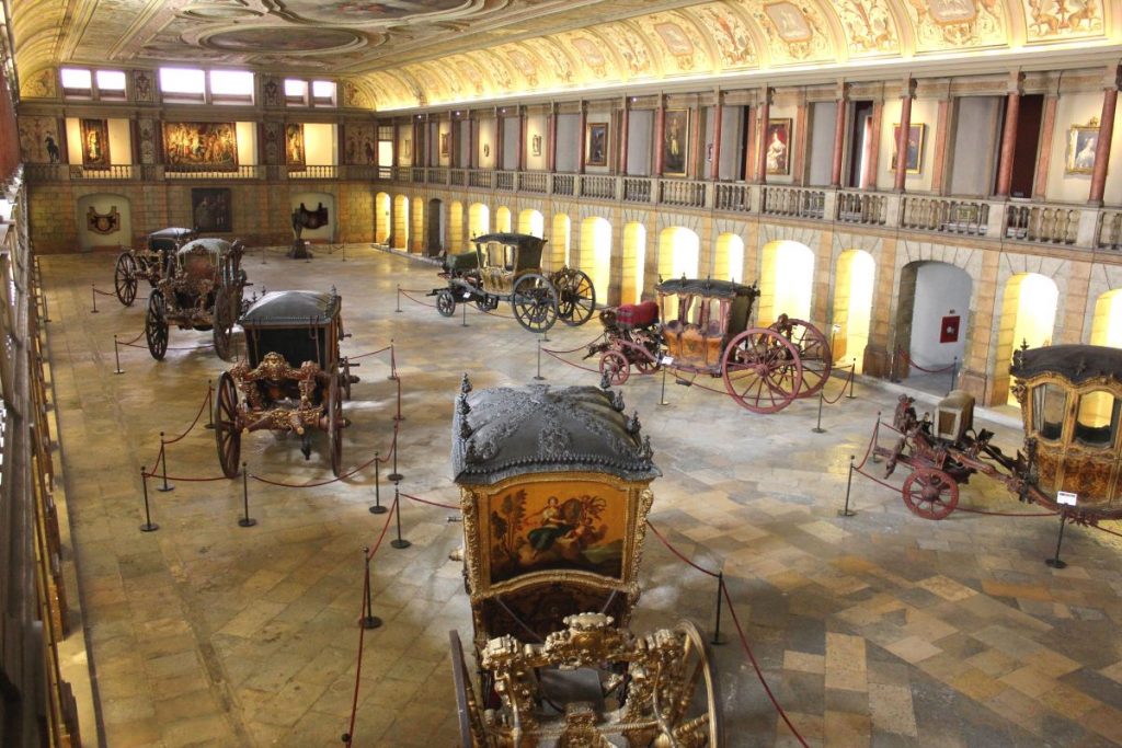 an ornate hall with painted ceilings, housing seven beautiful old fashioned coaches which were pulled by horses used by kings and queens - one of the exhibits int he Coach museum, one of the unusual museums in Lisbon.