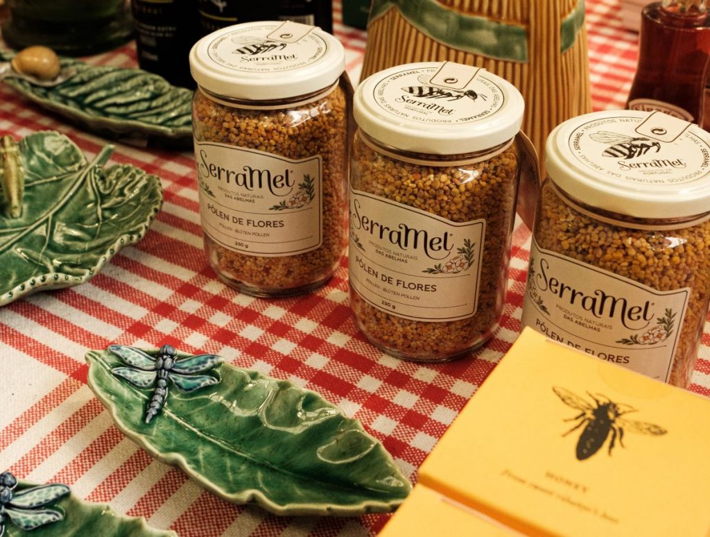 3 jars of bee pollen on display on a table with a red and white checked tablecloth and small green display dishes