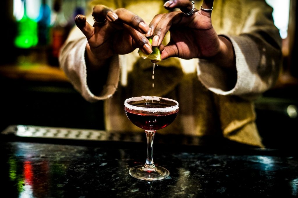 A person squeezes fresh lime juice into a sugared-rim cocktail at a trendy bar near Madrid’s Prado Museum.