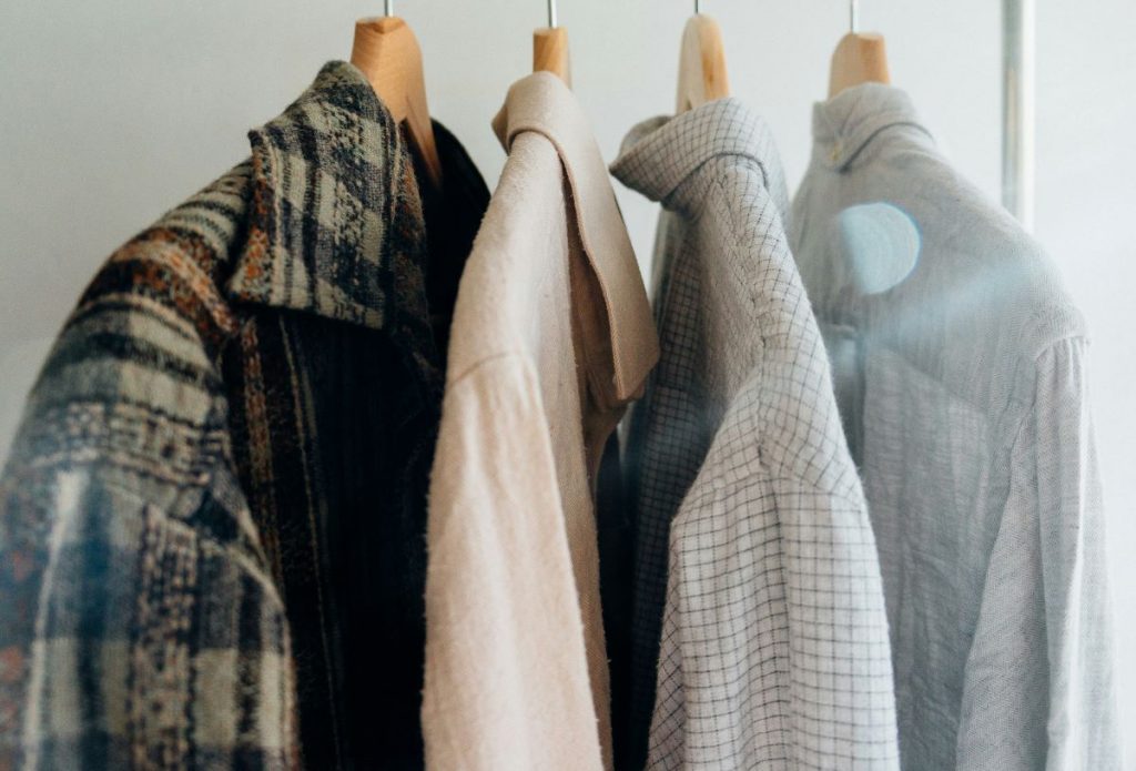 4 mens shirts made out of sustainable fabrics hung on hangers in a range of colours