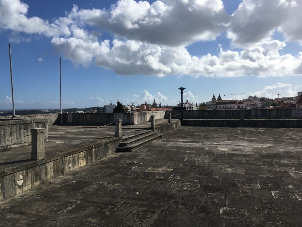 a flat stone rooftop with a blue sky above, which offers views of lisbon city from the Mãe d'Água das Amoreiras Reservoir