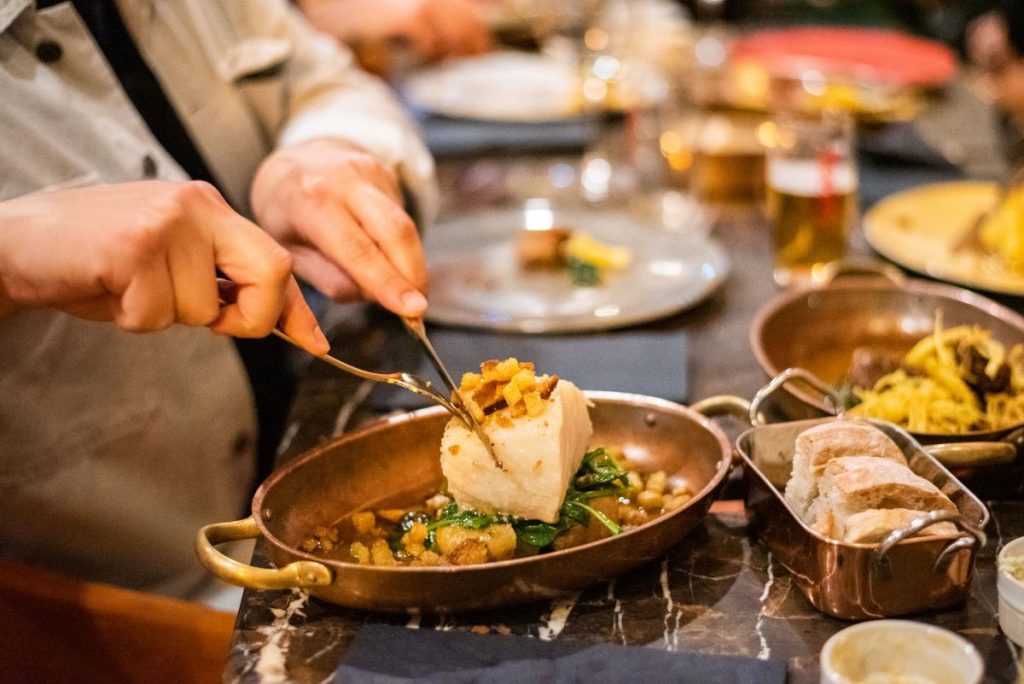 A person cutting into their bacalhau at a restaurant.
