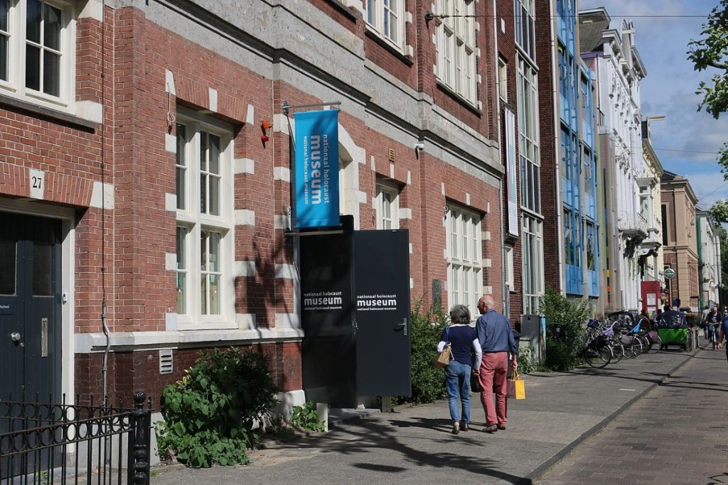 Two people walking around the Amsterdam Jewish Quarter outside of the National Holocaust Museum.