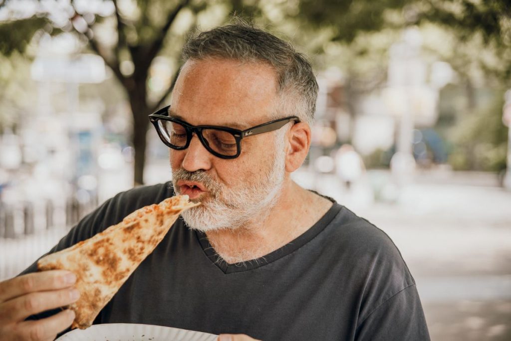 A man eating a slice of cheese pizza.