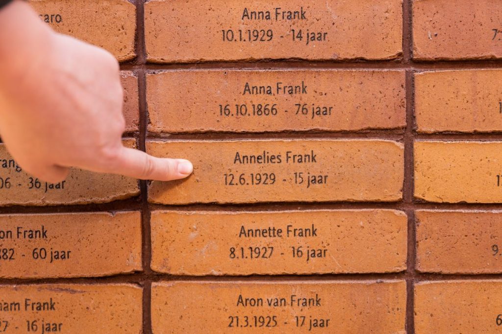 A woman pointing a brick with a name of someone who was killed during the Holocaust.