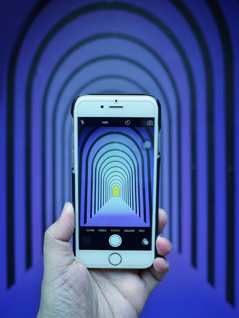 A person using their phone to take a picture of an optical illusion.