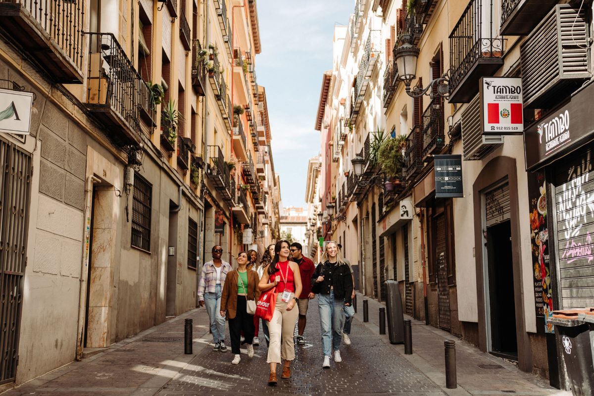 A tour guide takes a group of people through one of the Madrid neighborhood areas, learning the origin behind the names 