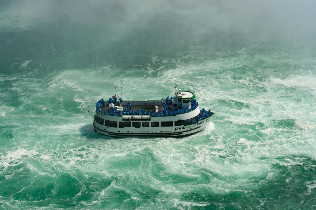 A boat with tourists on it visiting the Niagara Falls.