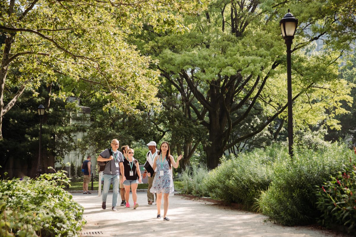 A group of people chatting and walking through Battery Park.