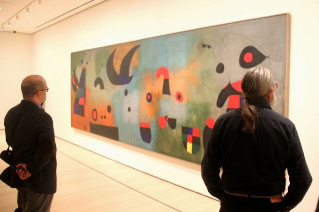 People looking at a Joan Miró painting.