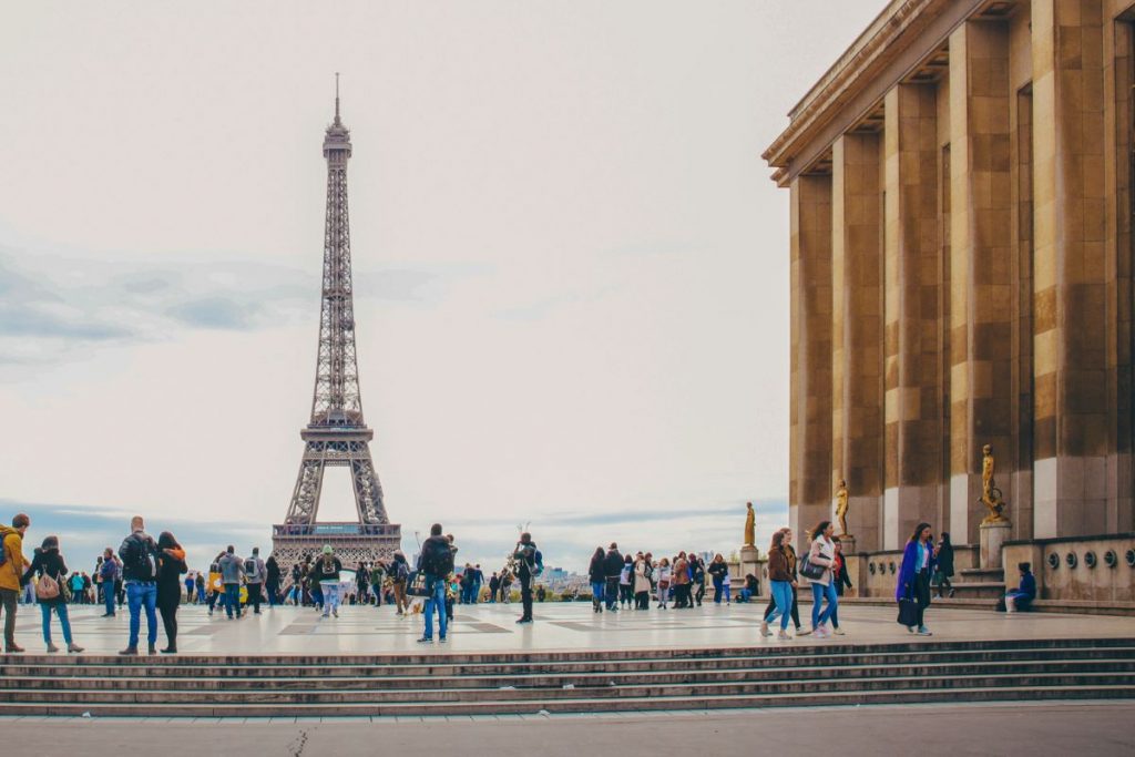 Visitors at Trocadéro capture photos of the Eiffel Tower; dramatic clouds loom over the vibrant Paris scene. When you take a solo trip to Paris, you can enjoy the sights on your own terms