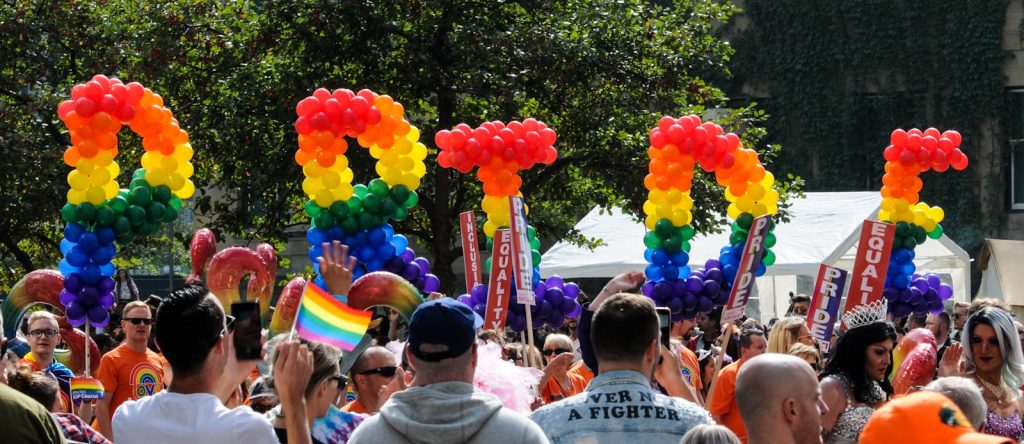 the leters P R I D E in rainbow colours are carried aloft the heads of people in a crowd at the Pride event in a Barcelona Gay Neighborhood