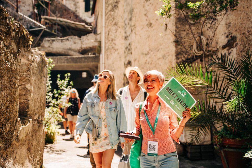 A Rome travel guide and a small group of tourists enjoy an historical site in the sunshine