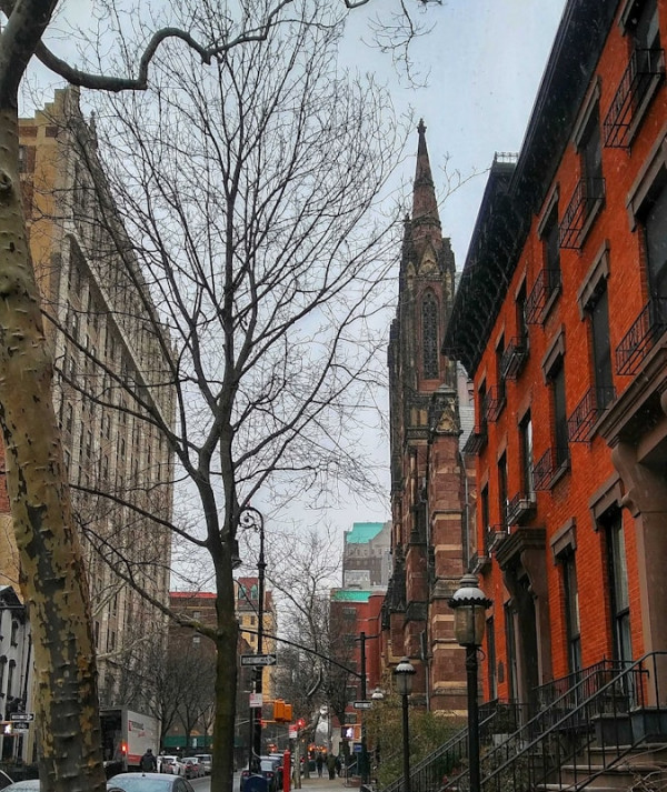 a city street lined with parked cars and tall buildings