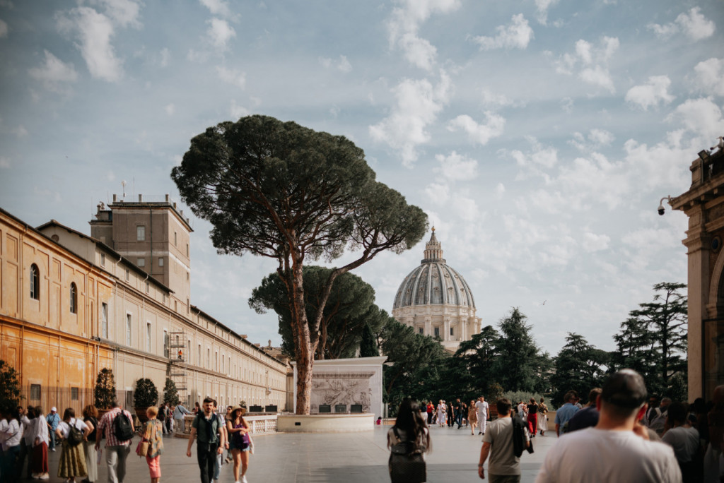 Visitors walk through the Vatican Museums courtyard in Rome toward the dome of Saint Peter’s Basilica.