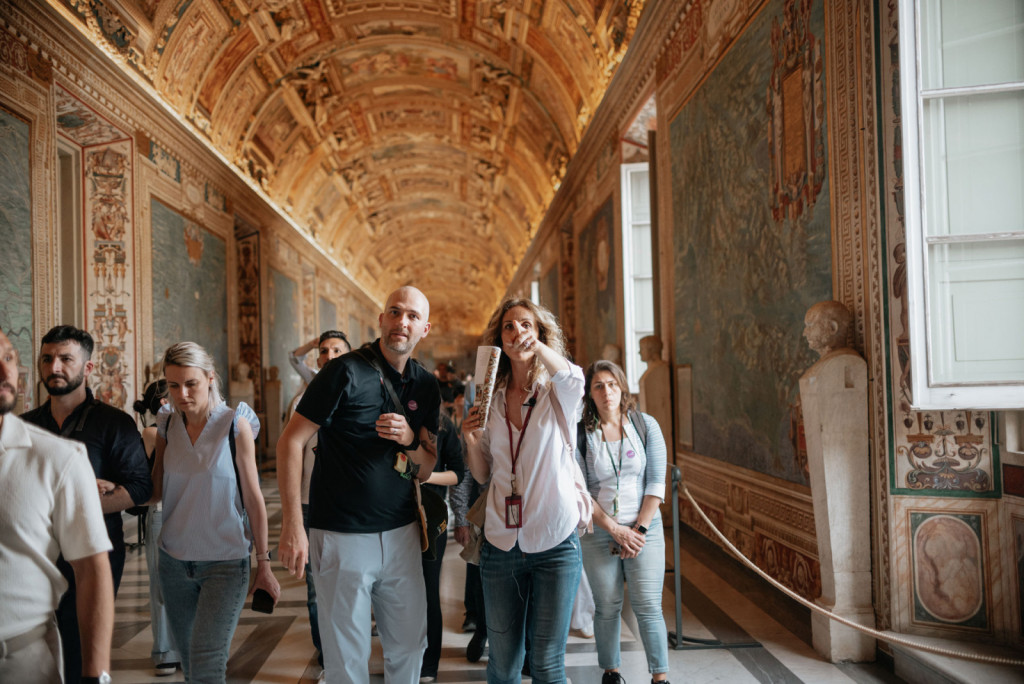 A guide points to the vaulted ceiling for a tour group in the Vatican Museums’ Gallery of Maps.